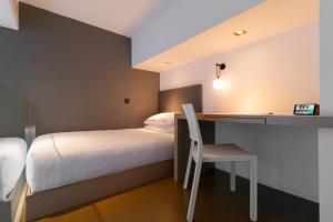 a bedroom with a bed and a desk and a bed and a chair at Studio M Hotel Singapore in Singapore +57 photos
