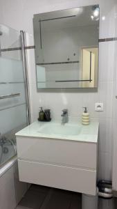 a white bathroom with a sink and a mirror at Cozy Suite La Défense in Nanterre