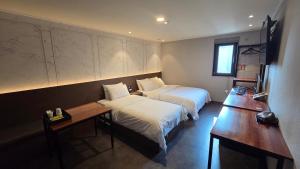ein Hotelzimmer mit zwei Betten und einem Schreibtisch in der Unterkunft Hotel Cleo in Goyang