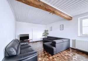 a living room with a black couch and a tv at Zur alten schule in Amblève