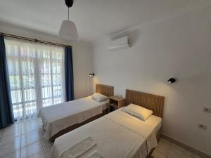 a bedroom with two beds and a large window at Golden Pension in Patara