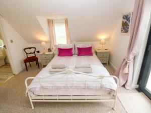 a bedroom with a white bed with pink pillows at North Studdock Cottage in Pembroke