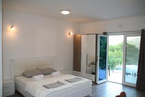 a white bedroom with a bed and a sliding glass door at B&I apartmani in Glavatske Kućice