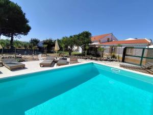 a large blue swimming pool with chairs and umbrellas at Casa do Lagar in Óbidos