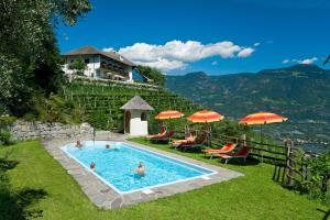 - un groupe de personnes dans une piscine avec une maison dans l'établissement Hotel Garni Vigilhof, à Lana