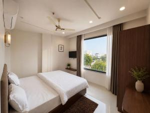 a bedroom with a white bed and a large window at Hotel RajKailash in Jaipur