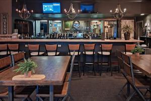 a bar with wooden tables and chairs in a restaurant at Clarion Inn Grand Junction Airport in Grand Junction