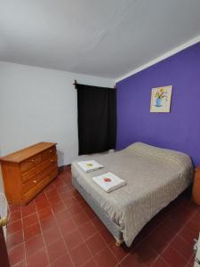 a bedroom with a bed and a dresser and purple wall at La casita de José in Villa Unión