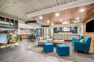 a waiting room with blue chairs and a tv at Clarion Pointe Richmond North near University in Richmond