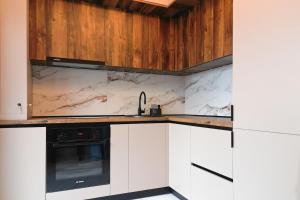 a kitchen with white cabinets and a black appliance at Luxury Studio Chiajna in Roşu