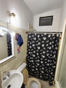 a bathroom with a shower curtain with a toilet and a sink at La casita de José in Villa Unión