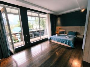 a bedroom with a bed and two large windows at Fortuna Gabala Boutique Hotel & Restaurant in Gabala