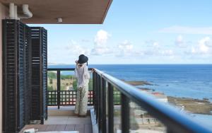 a woman standing on a balcony looking out at the ocean at Hotel Shigira Mirage in Miyako-jima
