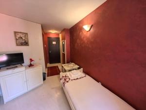a small room with a bed and a red wall at Hotel Trakia in Plovdiv