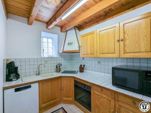 a kitchen with wooden cabinets and a sink and a microwave at Au cabanous in Boutx +22 photos