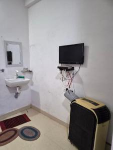 a bathroom with a tv and a sink in a room at Serene Farmhouse in Nimarkheri