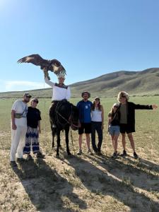 a group of people standing around a man holding an eagle at Rest House in Bokonbayevo