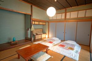 a room with two beds and a table in it at ISEZI Historic Machiya in Shibata