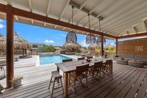 a deck with a table and chairs and a swimming pool at El Patrón, the villa in Jan Thiel