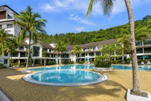 a swimming pool in front of a resort with palm trees at Sunday Residence Inn Cherating in Cherating