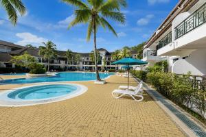 a chair and an umbrella next to a swimming pool at Sunday Residence Inn Cherating in Cherating