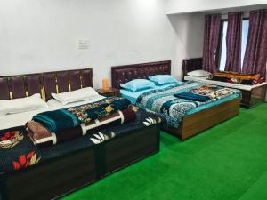 two beds in a room with green carpet at My Chopta Resort in Sari
