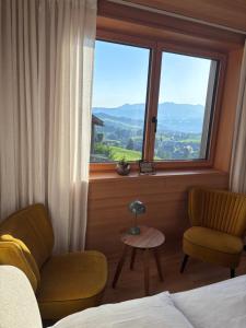 a bedroom with a bed and a chair and a window at Panoramazimmer im Bregenzerwald in Schwarzenberg
