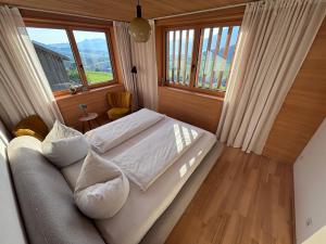a bedroom with a bed and a couch and windows at Panoramazimmer im Bregenzerwald in Schwarzenberg