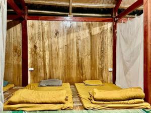 two beds in a room with a wooden wall at Homstay A Lệnh in Sơn La
