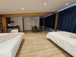 a room with two beds and a table and chairs at Les Logis des Treize-Vents à 15 minutes du Puy duFou in Treize-Vents