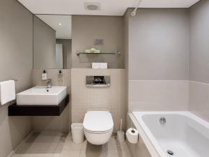 a bathroom with a toilet and a sink and a tub at Modern Ocean View Apartment in Cape Town +13 photos