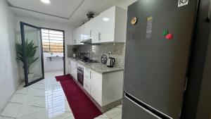 a kitchen with a refrigerator and a red rug at Airport's Layover Apartment in Nouaceur