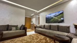 a living room with a couch and a tv on the wall at Airport's Layover Apartment in Nouaceur