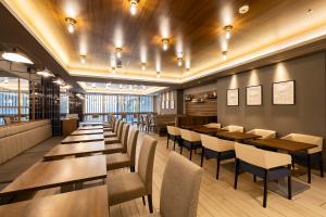 a restaurant with tables and chairs in a room at KOKO HOTEL Sapporo Susukino 2ⁿᵈ in Sapporo