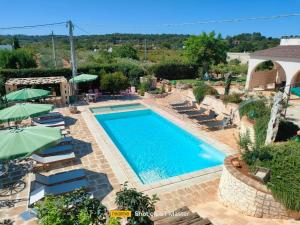 a pool with chairs and umbrellas in a resort at Casolare Lodedo in Ceglie Messapica