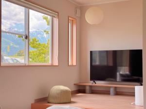 a living room with a flat screen tv and a window at Yamamori House in Hakuba