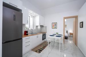 a kitchen with white cabinets and a table and a refrigerator at Nerea Eleon Residences in Eleonas