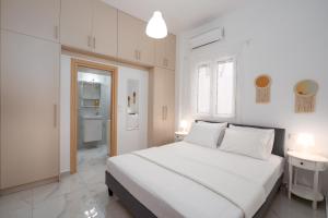 a white bedroom with a large bed and a refrigerator at Nerea Eleon Residences in Eleonas