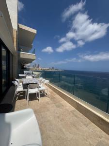 a balcony with a table and chairs and the ocean at Panoramic XL Penthouse Sliema Seafront in Sliema