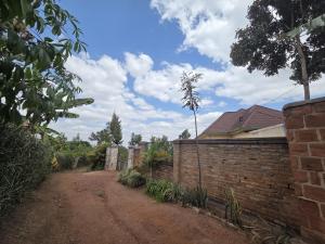 a dirt road next to a brick wall at Akagera Sunset House in Kabarondo
