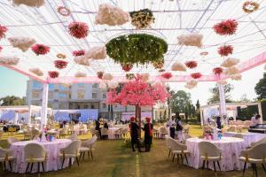 a banquet hall with white tables and pink flowers at Sagar Resort in Alwar