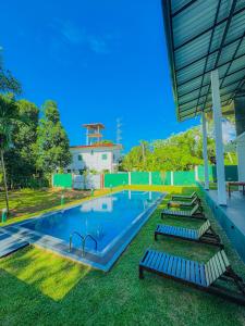 a swimming pool with lounge chairs in the grass at Nilwadula Hotel Udawalawe in Ratkarawwa