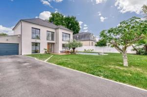 a large white house with a garage at House Moringa Rituals Pool in Le Plessis-Trévise