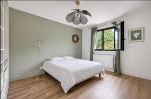 a white bedroom with a bed and a window at House Moringa Rituals Pool in Le Plessis-Trévise