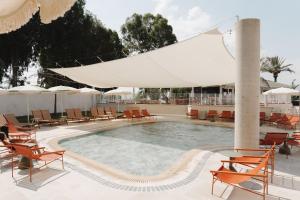 a swimming pool with chairs and umbrellas on a resort at Nof Ginosar Kibbutz Hotel in Kibbutz Ginnosar