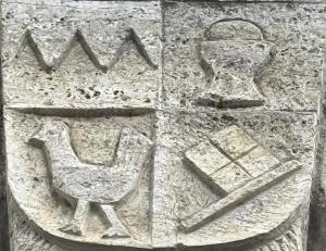 a stone wall with a relief of a chair and aries at Ankerplatz in Münnerstadt
