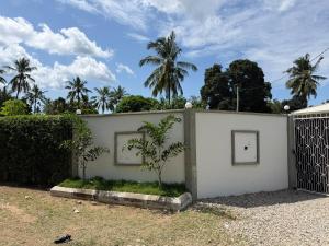 a white fence with a palm tree behind it at 2BR Apartment in Tanga in Tanga