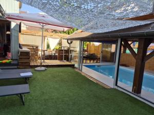 a house with a swimming pool and an umbrella at Hotel De Paris in Poligny