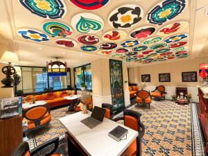 a living room with a ceiling covered in colorful artwork at Eliana Robusta Hotel in Hanoi