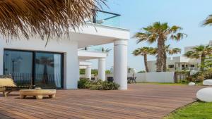 a white house with a wooden deck and palm trees at Jacob Sea Life Nahariya in Nahariyya